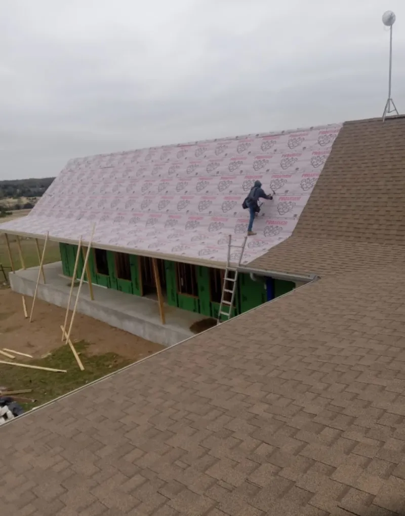 Worker preparing underlayment for a metal roof installation in Rupert